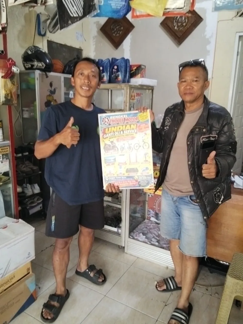 Pelanggan dan pemilik bengkel memegang poster undian