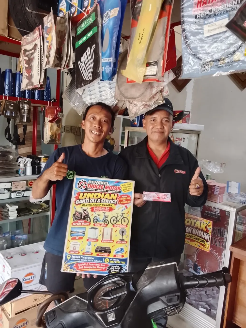 Tim bengkel dan pelanggan memegang poster dan kupon undian