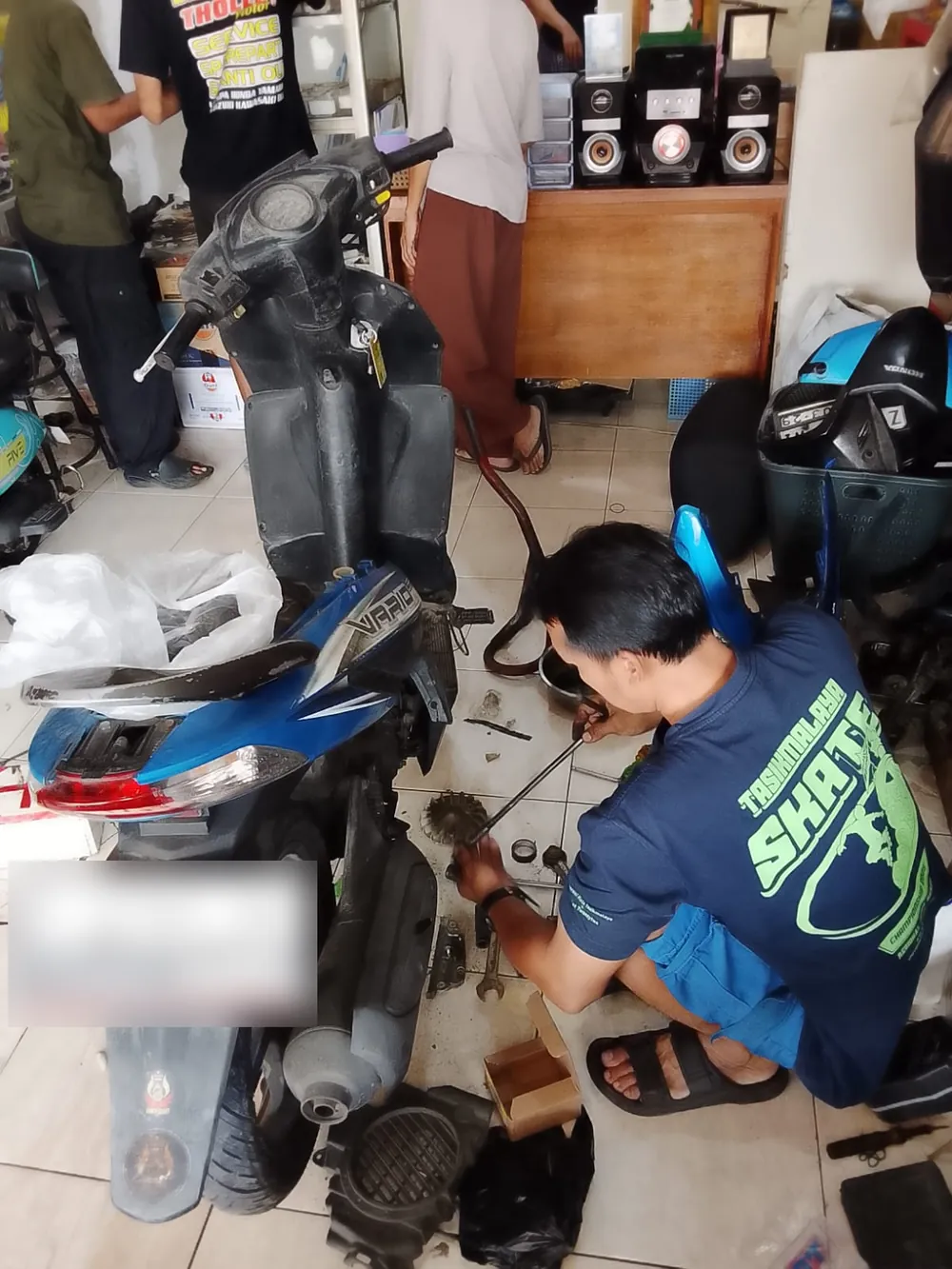 Mekanik sedang mengerjakan motor di bengkel